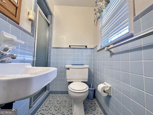 bathroom featuring tile walls, toilet, a shower with door, and tile patterned flooring