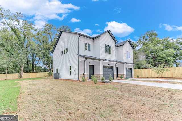 view of front of home featuring a front yard, a garage, and central AC unit