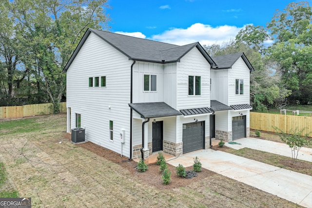 view of front of property featuring a front yard, a garage, and central AC