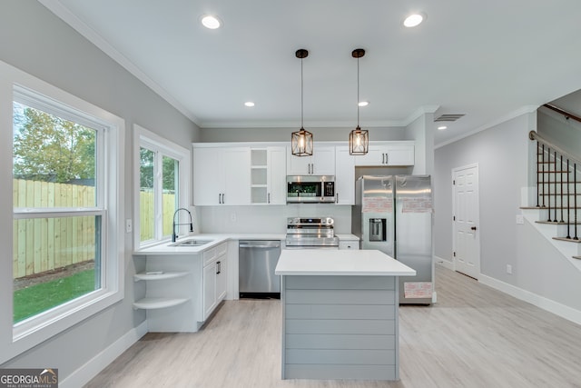 kitchen featuring hanging light fixtures, stainless steel appliances, a kitchen island, white cabinets, and sink