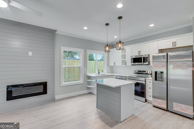 kitchen featuring stainless steel appliances, pendant lighting, a kitchen island, sink, and white cabinetry