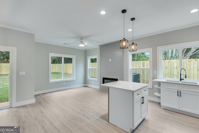 kitchen featuring a center island, pendant lighting, a fireplace, sink, and white cabinetry