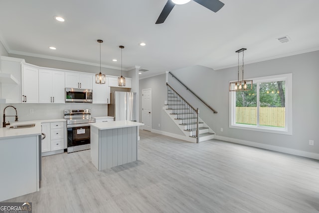 kitchen featuring stainless steel appliances, a center island, pendant lighting, and sink