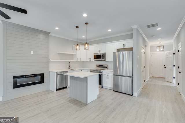 kitchen with appliances with stainless steel finishes, a center island, pendant lighting, white cabinets, and sink