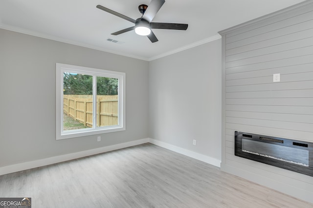 unfurnished living room featuring a large fireplace, ceiling fan, crown molding, and light hardwood / wood-style flooring