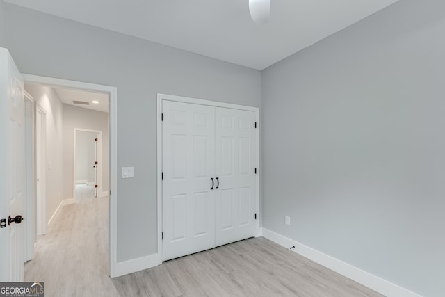 unfurnished bedroom featuring ceiling fan, light wood-type flooring, and a closet