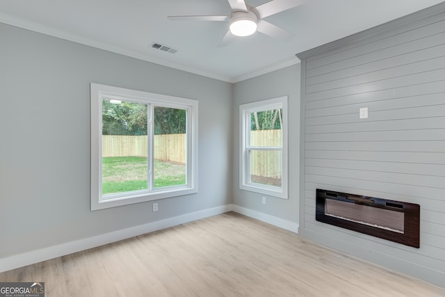 unfurnished living room featuring a large fireplace, light hardwood / wood-style floors, crown molding, heating unit, and ceiling fan