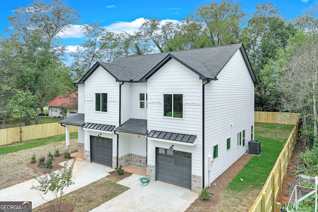 modern farmhouse style home featuring cooling unit, a garage, and a front yard