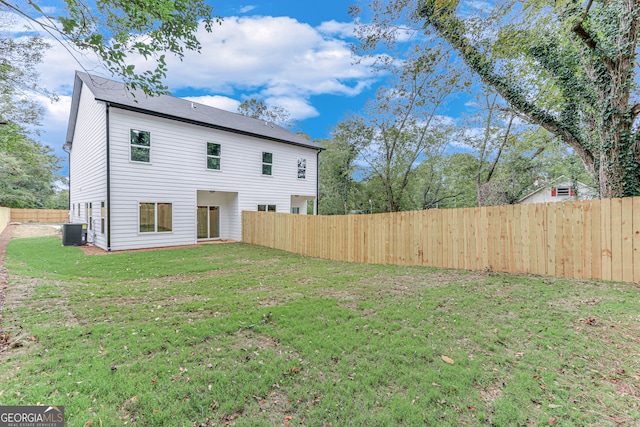 back of property featuring a yard and central AC