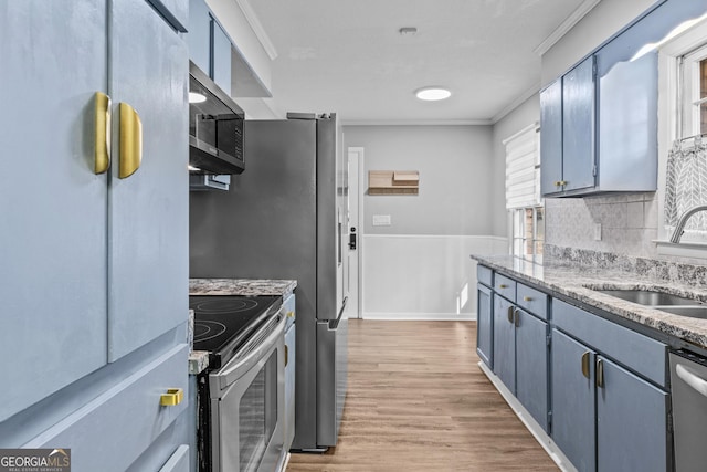 kitchen featuring light stone counters, light hardwood / wood-style floors, appliances with stainless steel finishes, ornamental molding, and sink