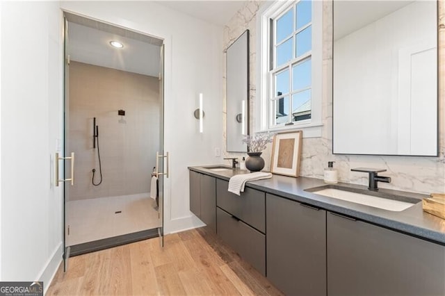 bathroom with tasteful backsplash, vanity, hardwood / wood-style floors, and a shower with shower door