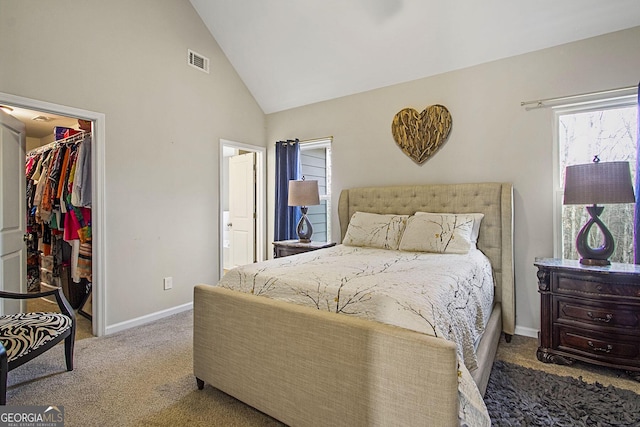 bedroom featuring a walk in closet, high vaulted ceiling, a closet, and carpet