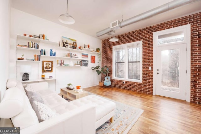 living room with brick wall and light wood-type flooring