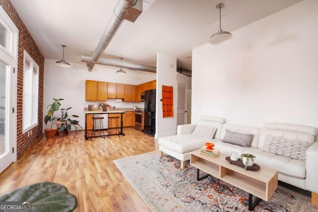 living room with brick wall, light wood-type flooring, and sink