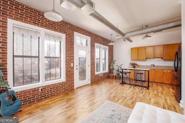 kitchen featuring brick wall, black fridge, dishwasher, and hanging light fixtures