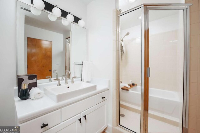 bathroom featuring a shower with door and vanity