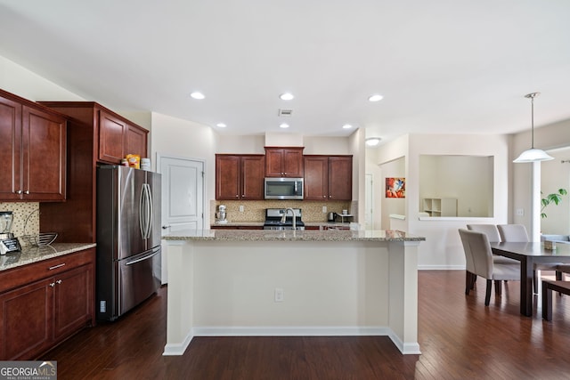 kitchen with pendant lighting, light stone countertops, a center island with sink, and appliances with stainless steel finishes