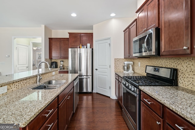 kitchen featuring light stone countertops, appliances with stainless steel finishes, tasteful backsplash, sink, and dark hardwood / wood-style flooring