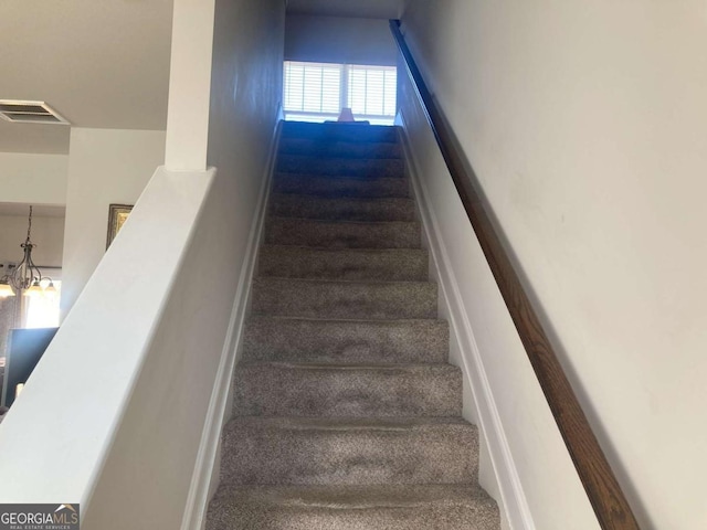 stairs featuring a chandelier