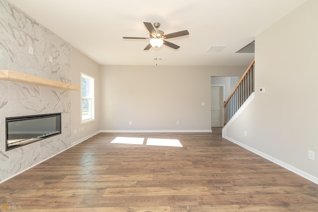 unfurnished living room featuring ceiling fan, a high end fireplace, and hardwood / wood-style flooring