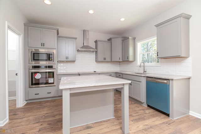 kitchen with appliances with stainless steel finishes, gray cabinets, sink, and wall chimney exhaust hood