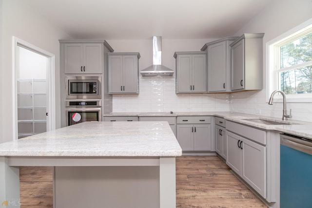 kitchen with stainless steel appliances, sink, tasteful backsplash, wall chimney range hood, and gray cabinetry