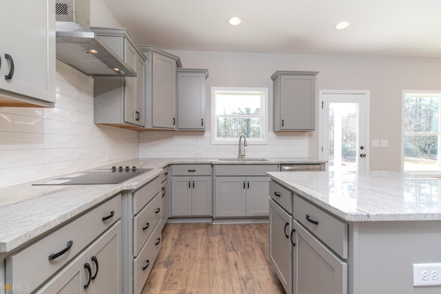 kitchen with sink, gray cabinetry, light wood-type flooring, and wall chimney range hood