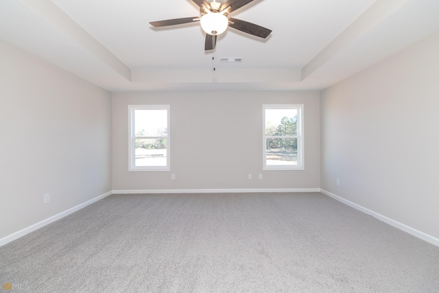 spare room featuring ceiling fan, carpet floors, and a tray ceiling