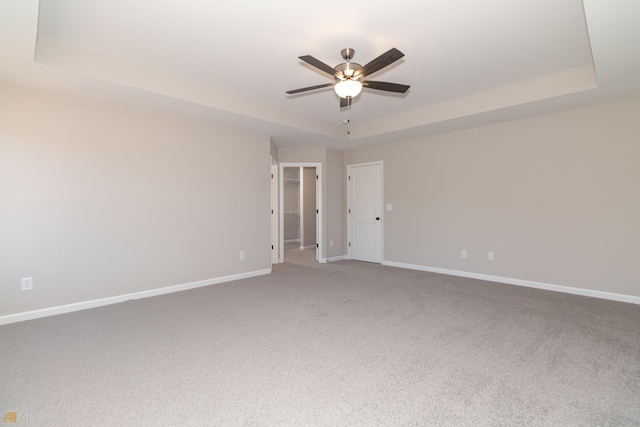 carpeted spare room with ceiling fan and a tray ceiling