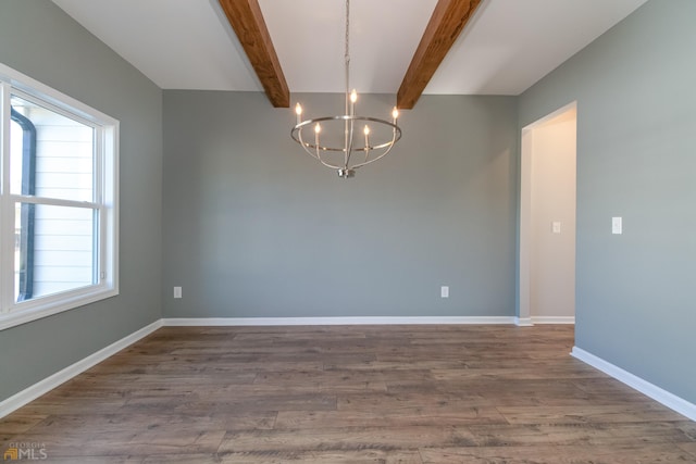 unfurnished room featuring a healthy amount of sunlight, a notable chandelier, hardwood / wood-style flooring, and beam ceiling