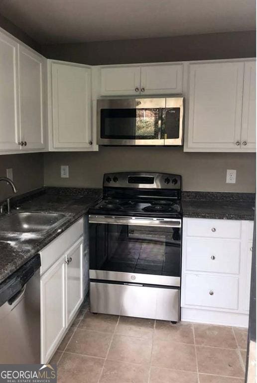 kitchen with light tile patterned flooring, stainless steel appliances, white cabinetry, and sink