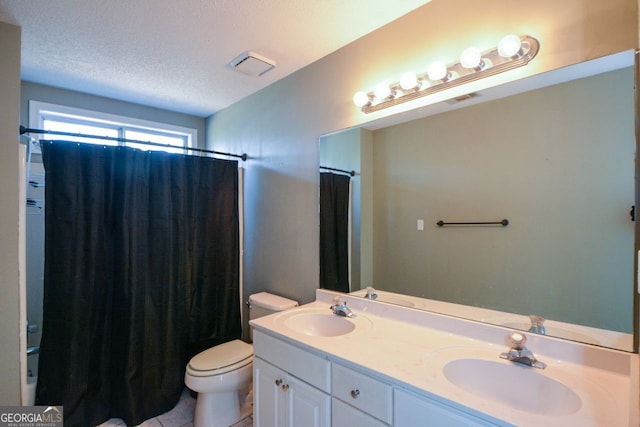 bathroom featuring tile patterned floors, vanity, toilet, and a textured ceiling