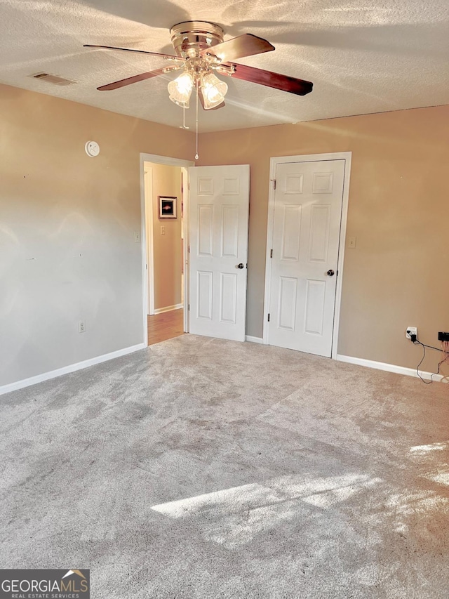 unfurnished bedroom with ceiling fan, carpet, and a textured ceiling