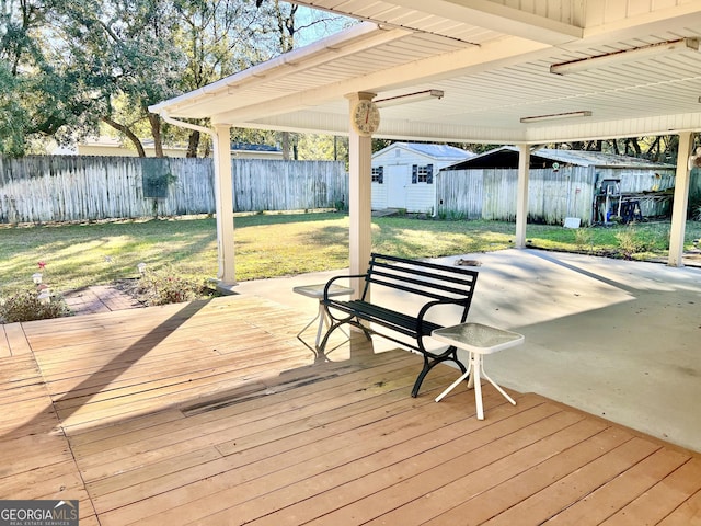 wooden deck featuring a yard, a storage unit, and a patio area