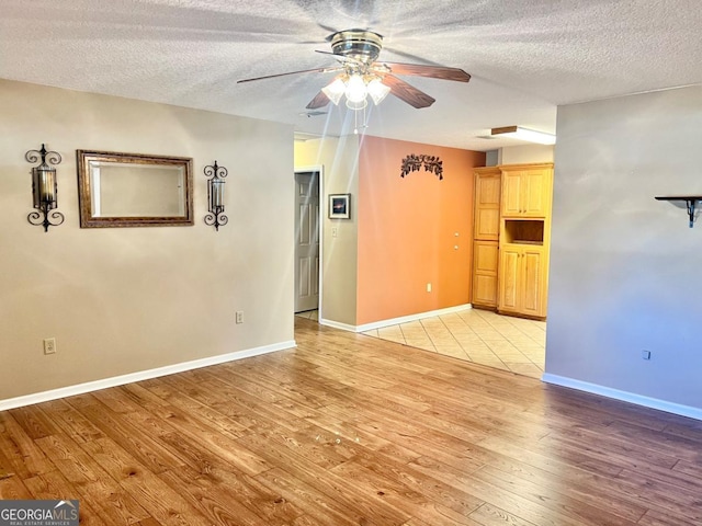 unfurnished room with a textured ceiling, ceiling fan, and light hardwood / wood-style floors