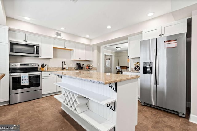 kitchen featuring stainless steel appliances, a kitchen island, white cabinets, and a kitchen breakfast bar