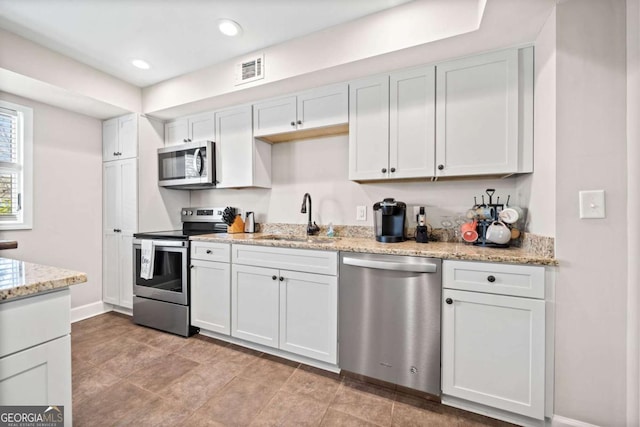 kitchen with sink, stainless steel appliances, white cabinetry, and light stone counters