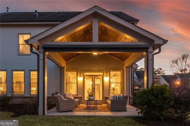 back house at dusk with a patio area and outdoor lounge area