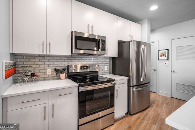 kitchen featuring white cabinets, light wood-type flooring, appliances with stainless steel finishes, and backsplash