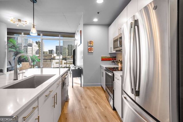 kitchen featuring decorative light fixtures, white cabinets, sink, and appliances with stainless steel finishes