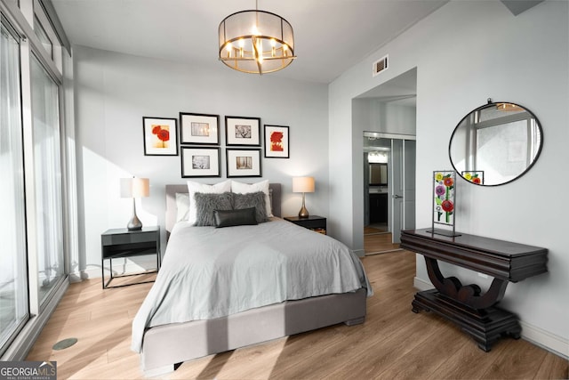 bedroom with light wood-type flooring, a chandelier, and multiple windows