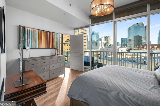 bedroom featuring a chandelier, light wood-type flooring, access to outside, and expansive windows