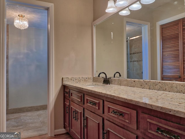 bathroom featuring a shower with door, vanity, and a chandelier