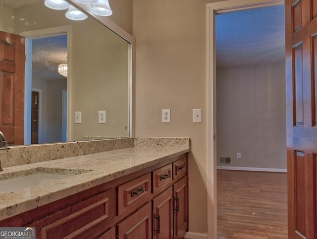 bathroom with an inviting chandelier, wood-type flooring, and vanity