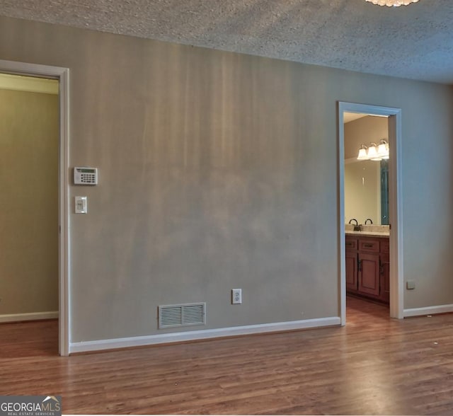 unfurnished room with a textured ceiling and light wood-type flooring