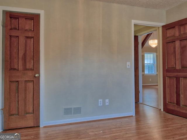 unfurnished room featuring a textured ceiling and light hardwood / wood-style flooring