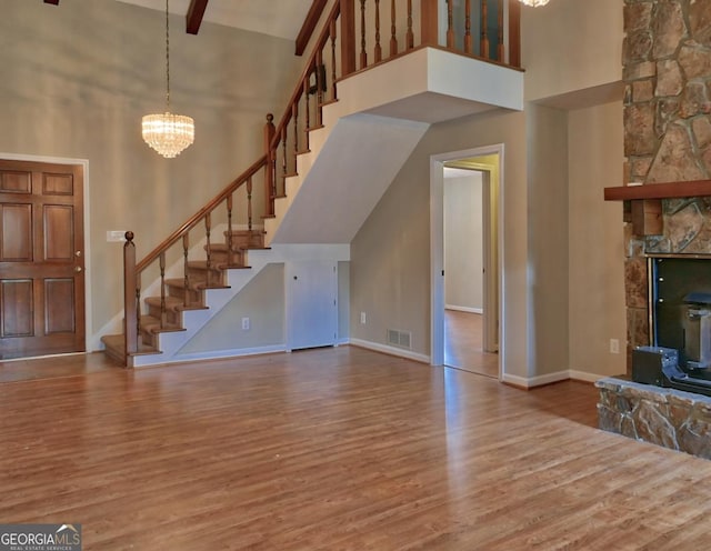 unfurnished living room with high vaulted ceiling, beam ceiling, and a chandelier