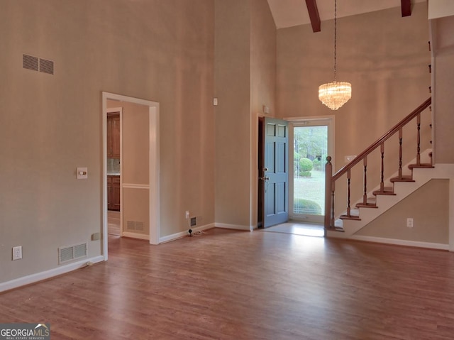 foyer entrance featuring a high ceiling, a notable chandelier, beamed ceiling, and hardwood / wood-style floors