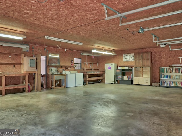 garage featuring white refrigerator and washing machine and clothes dryer