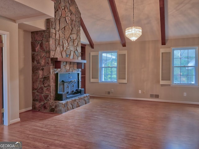 unfurnished living room featuring a chandelier, hardwood / wood-style floors, vaulted ceiling with beams, and a wood stove